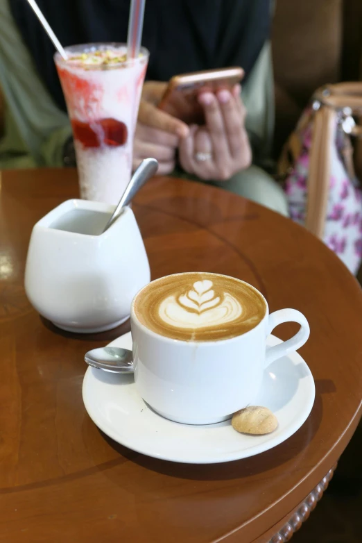 the cup with the milk cappuccino on is next to another cup