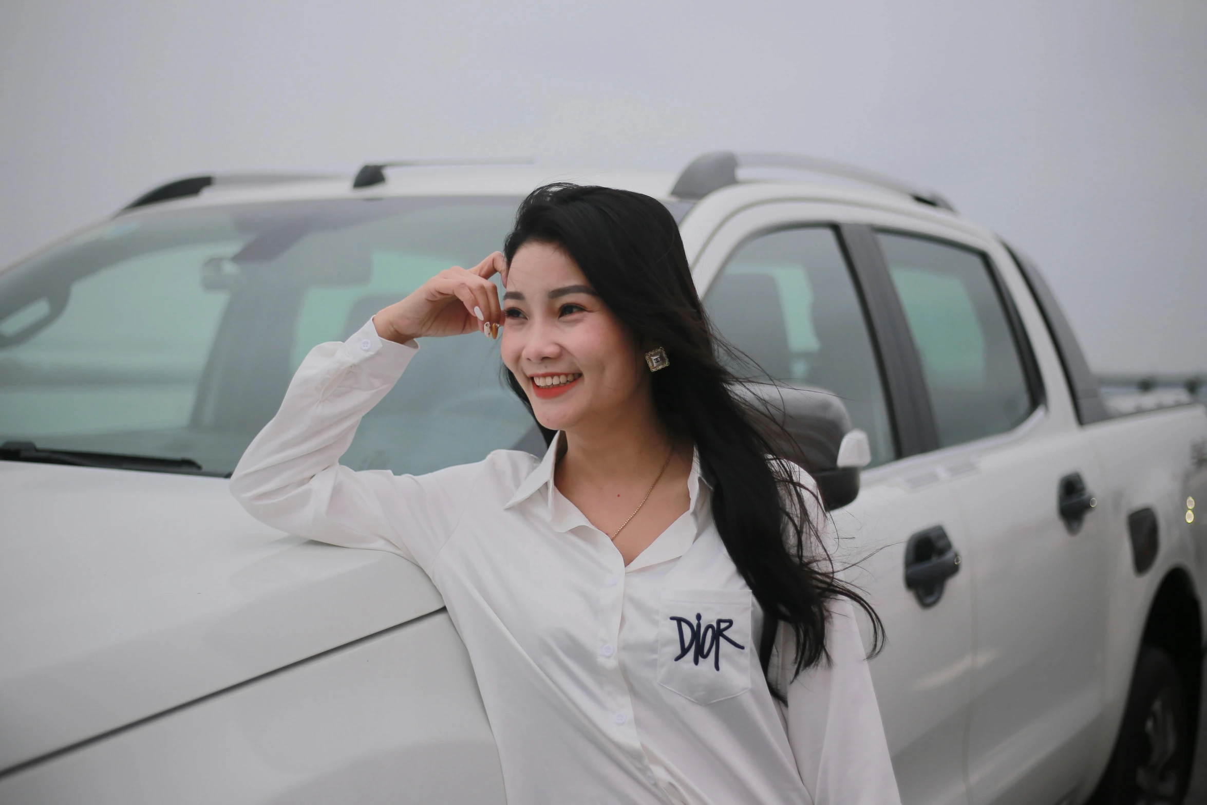 a young woman posing next to a white truck