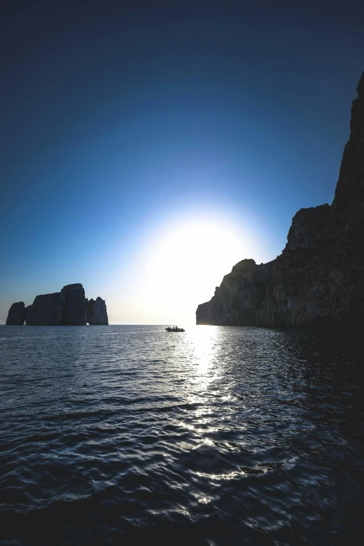 some boats floating on top of water with rocks in the distance