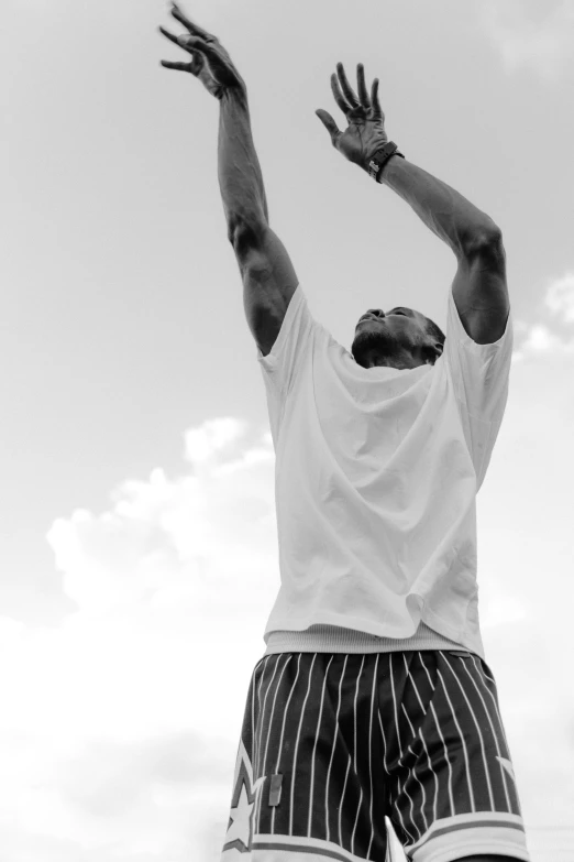 a man wearing a white shirt reaching up to catch a frisbee