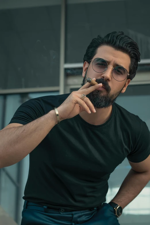 a man with dark hair and glasses smoking a cigarette