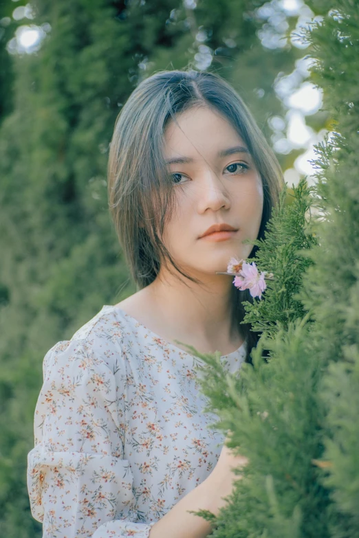 an asian woman holds out a small flower to her face