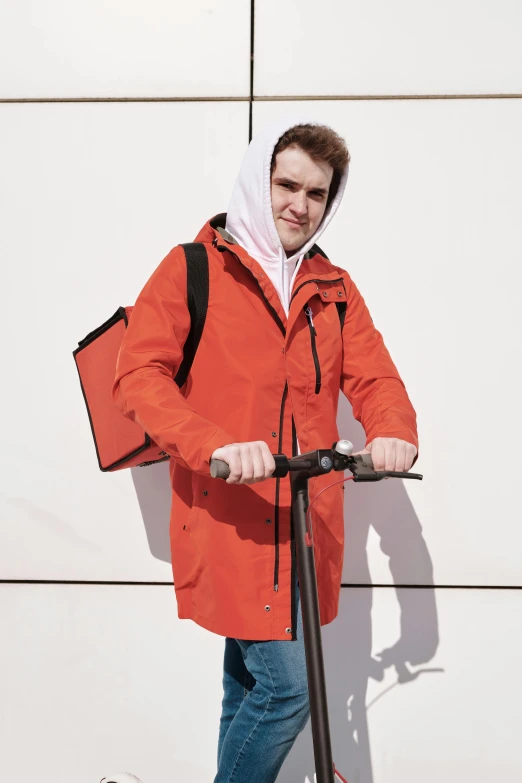 a man standing next to a white wall with a scooter