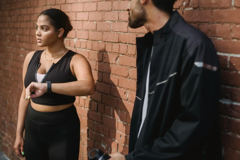 a man and woman standing against a brick wall