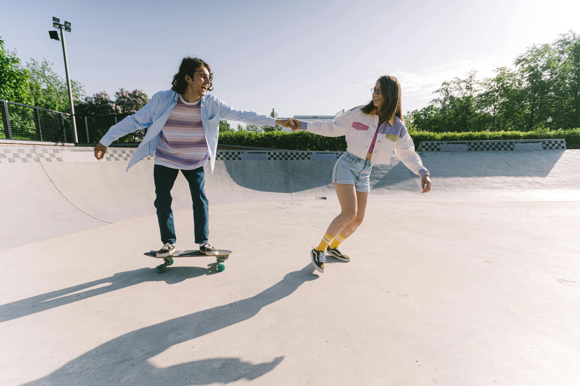 a man and woman skate boarding in an open area