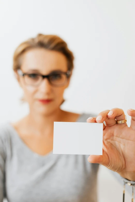 a woman is holding out a blank business card