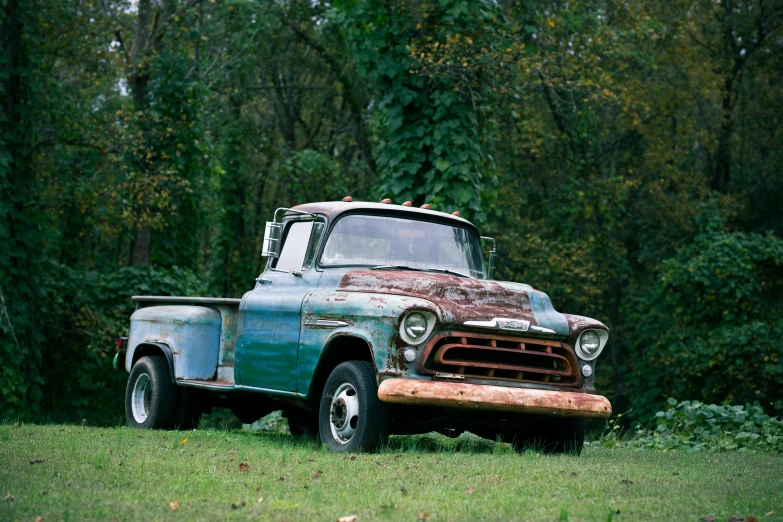 an old truck sits in the middle of some grass