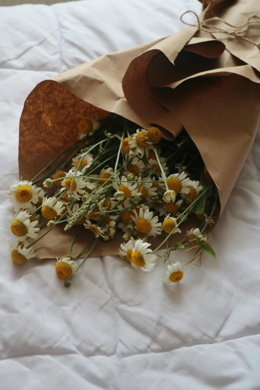 a paper bag filled with wildflowers on a bed