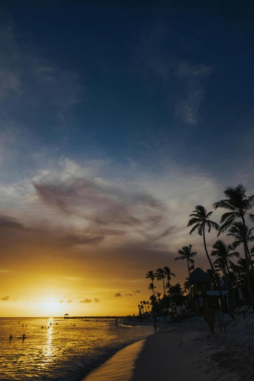 the sun is setting behind a beach with a couple walking on it