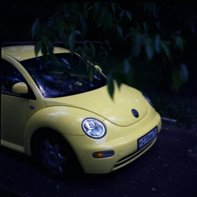 the small yellow car is parked next to the leaves