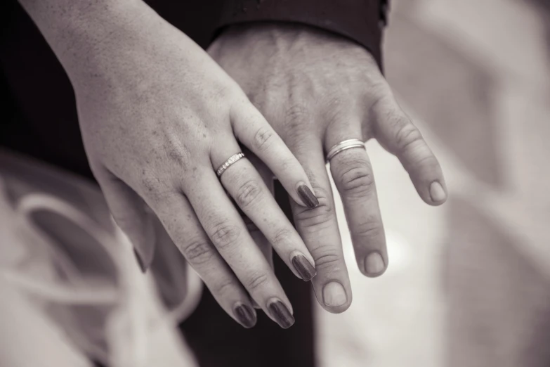 the newlywed couple hold hands with their fingers