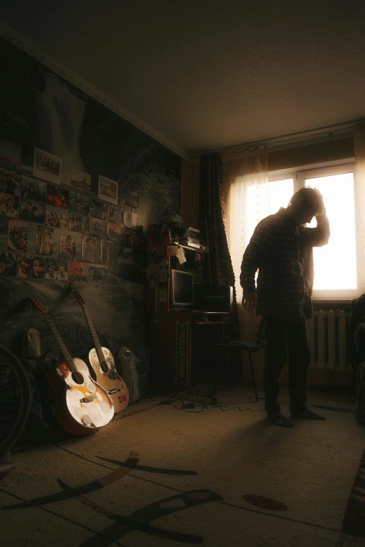 a man that is standing in a room near a guitar