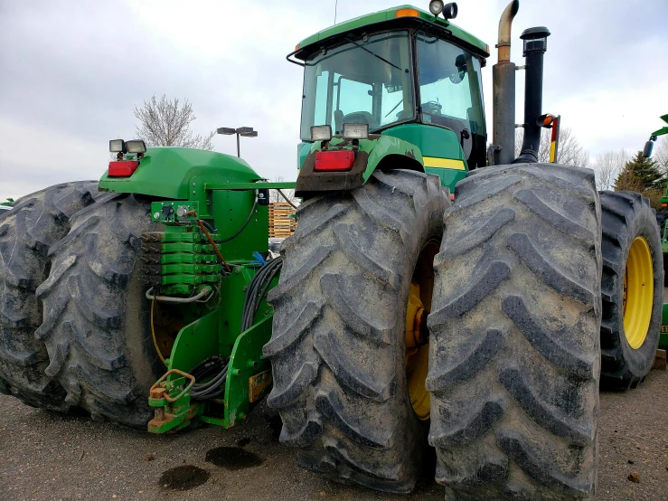 two large green tractors with yellow tires