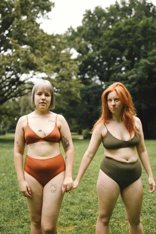 two plump women in bodysuits are standing on a field