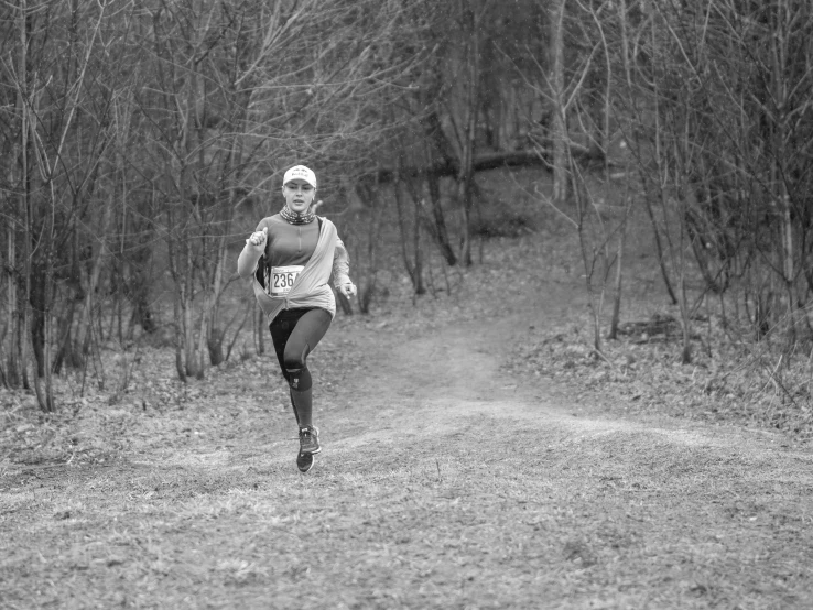 black and white po of a woman running on trail in woods