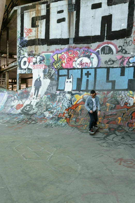 a skateboarder standing on the side of a wall covered in graffiti