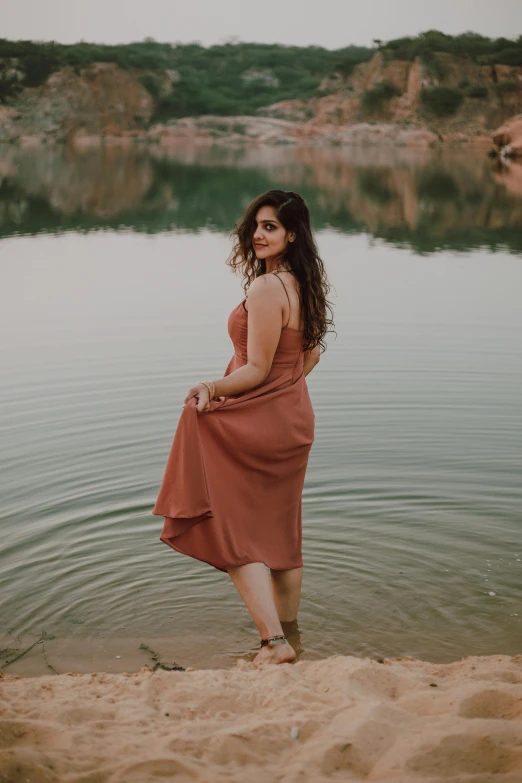 a woman in a red dress standing at the edge of water