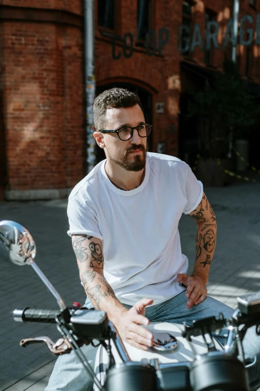 a man sitting on a motorcycle with tattoos on