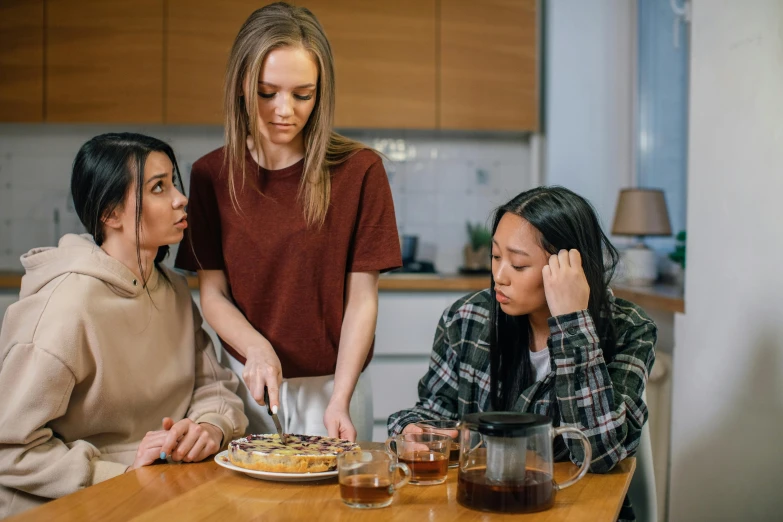 three young women are cooking food together in the kitchen