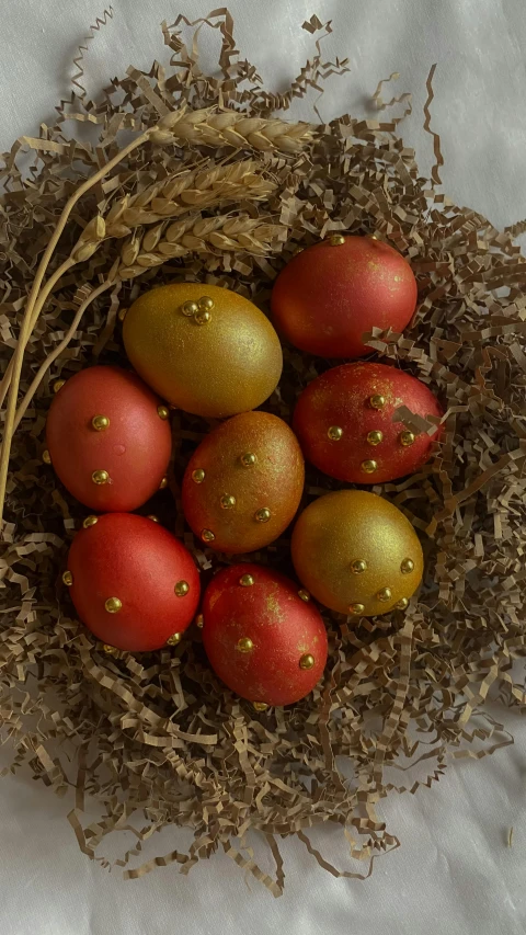 small red and yellow eggs in a nest with straw