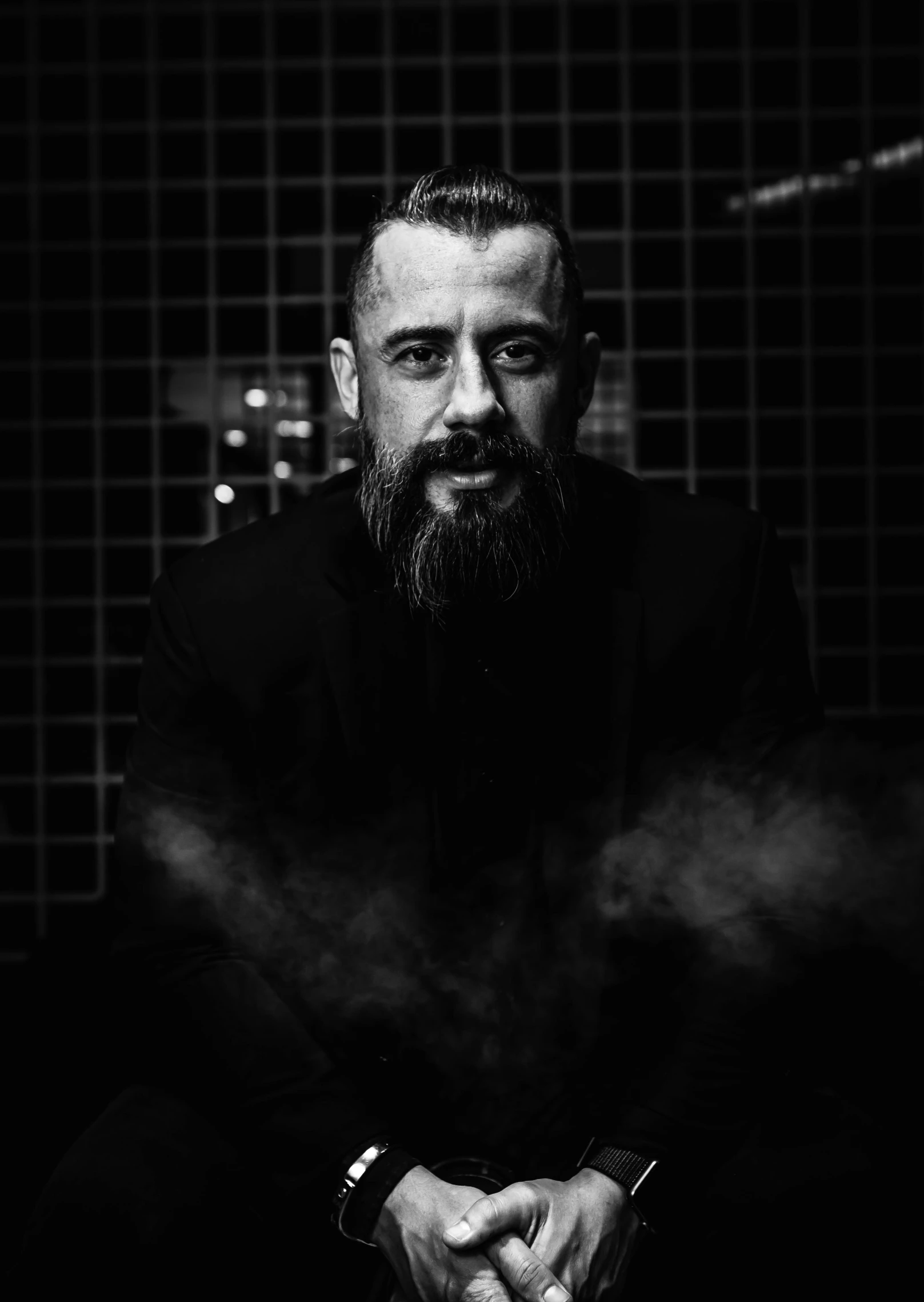 a man with beard sitting on the ground and smoking