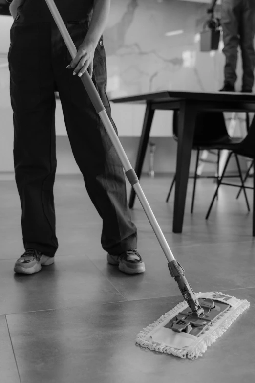 a person with a mop is standing on a hard wood floor