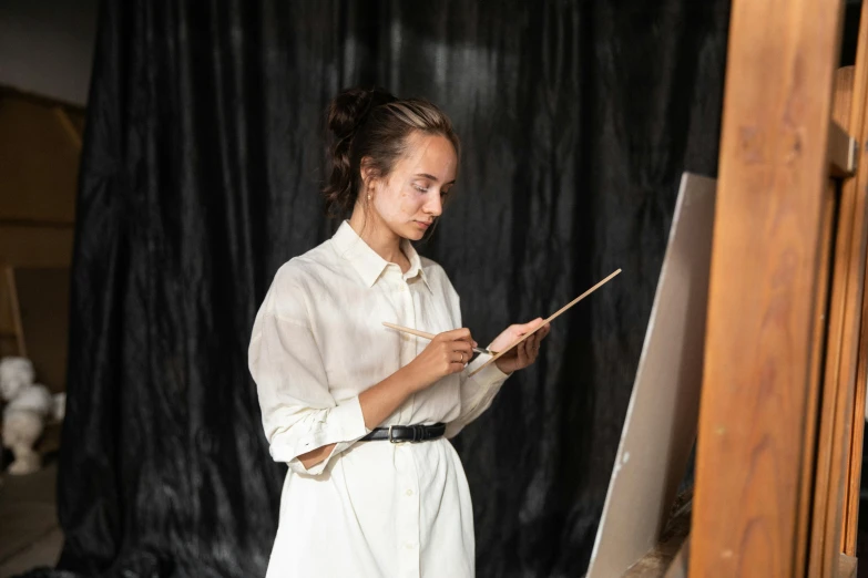 a woman is holding a wooden brush while working on a painting