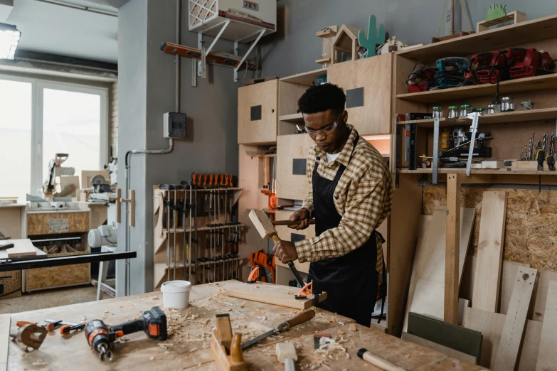 the man is in his workshop working on the wooden pieces