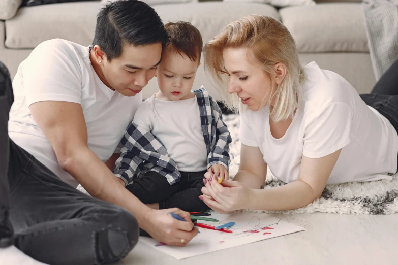 a woman sitting on the floor playing with her husband and child