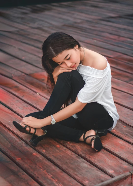 a young lady sits on a wooden floor and looks like she has fallen asleep