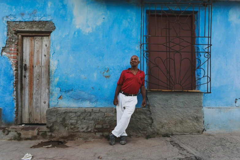 a man leaning against the corner of a blue wall