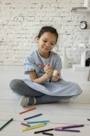 a child sits on the floor while holding a crayon