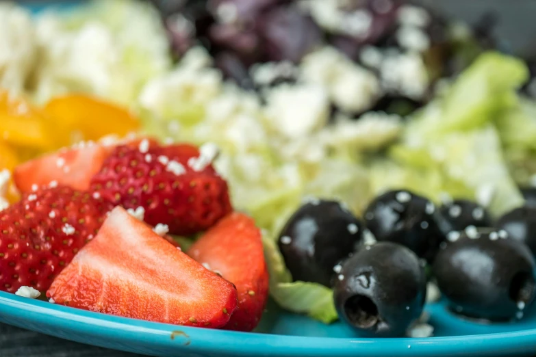 a blue plate of fruit is full of berries and other fruits