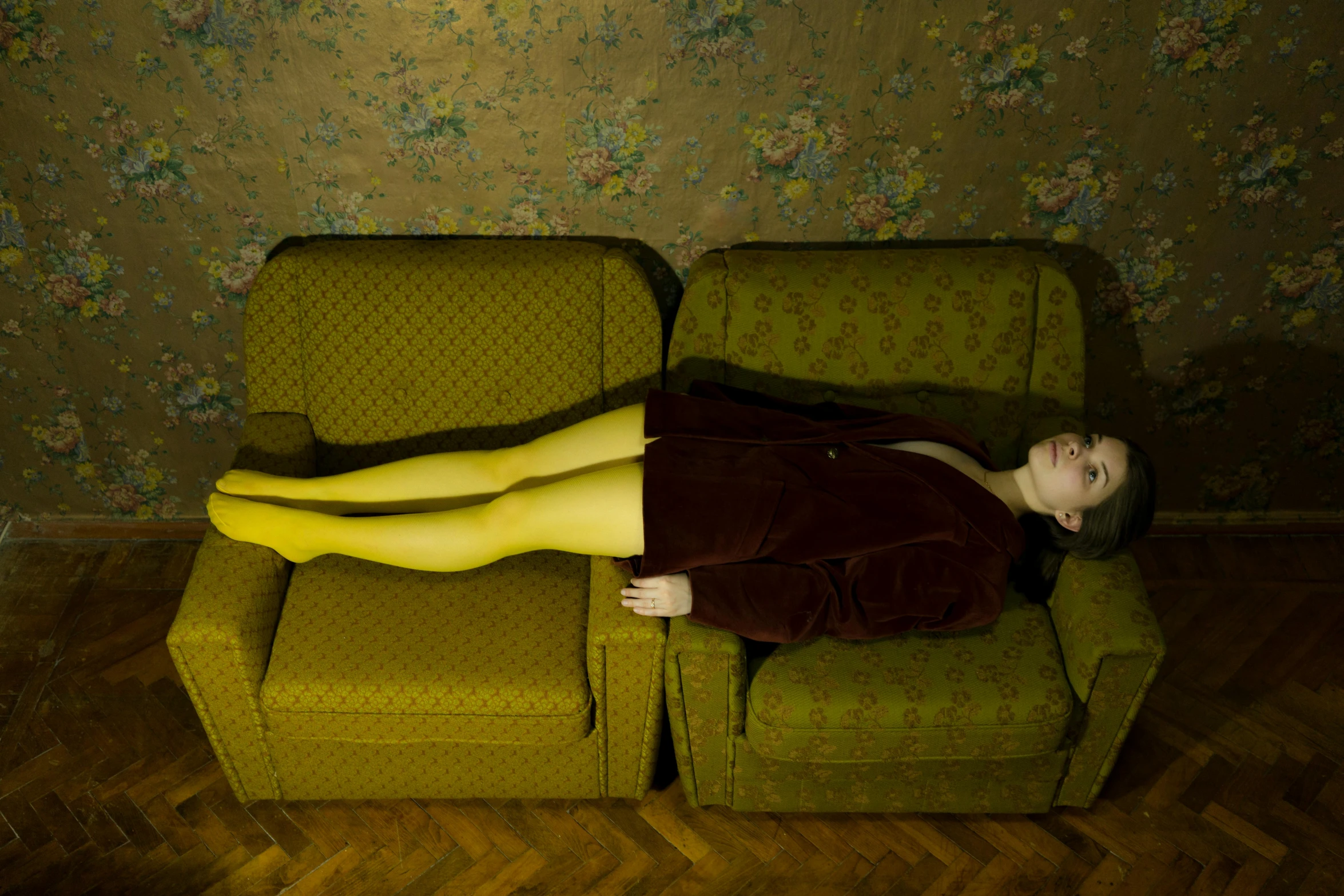 a woman lays on top of a couch in front of a wall with floral patterns