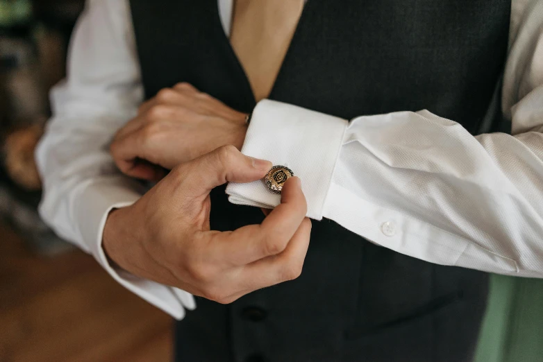 a person in a dress shirt and tie tying a wedding ring