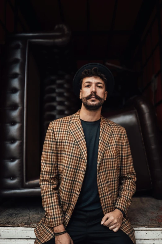 a man with a mustache sits in front of a building