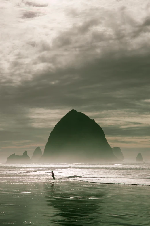 man walking into the ocean on a foggy day