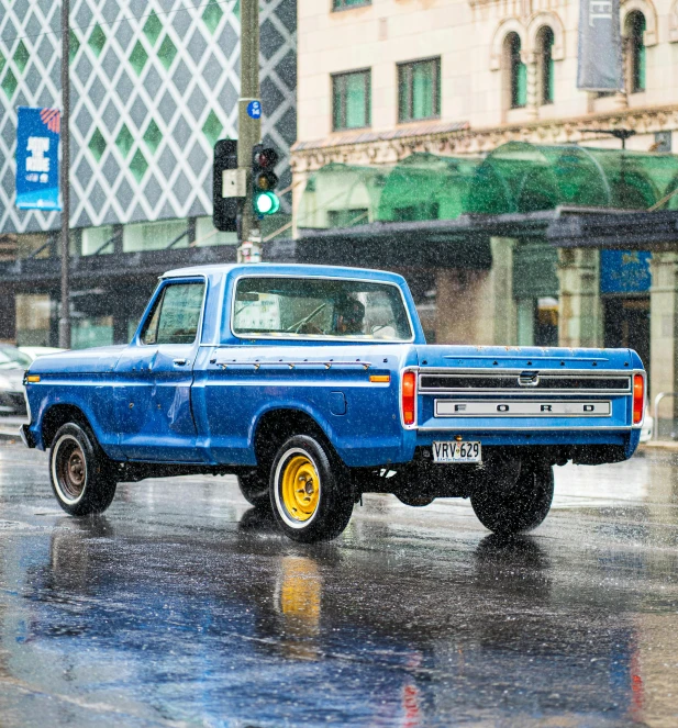 an old blue truck driving down the road