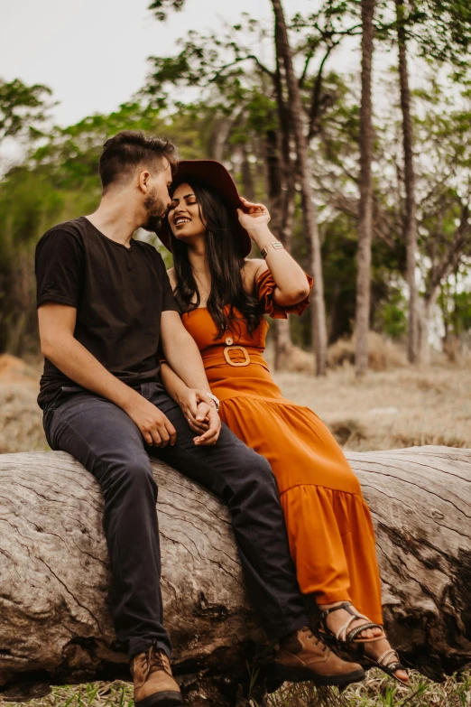 a man and a woman sitting on a log in the woods