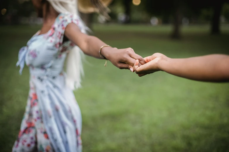 two women holding each other's hands in a field