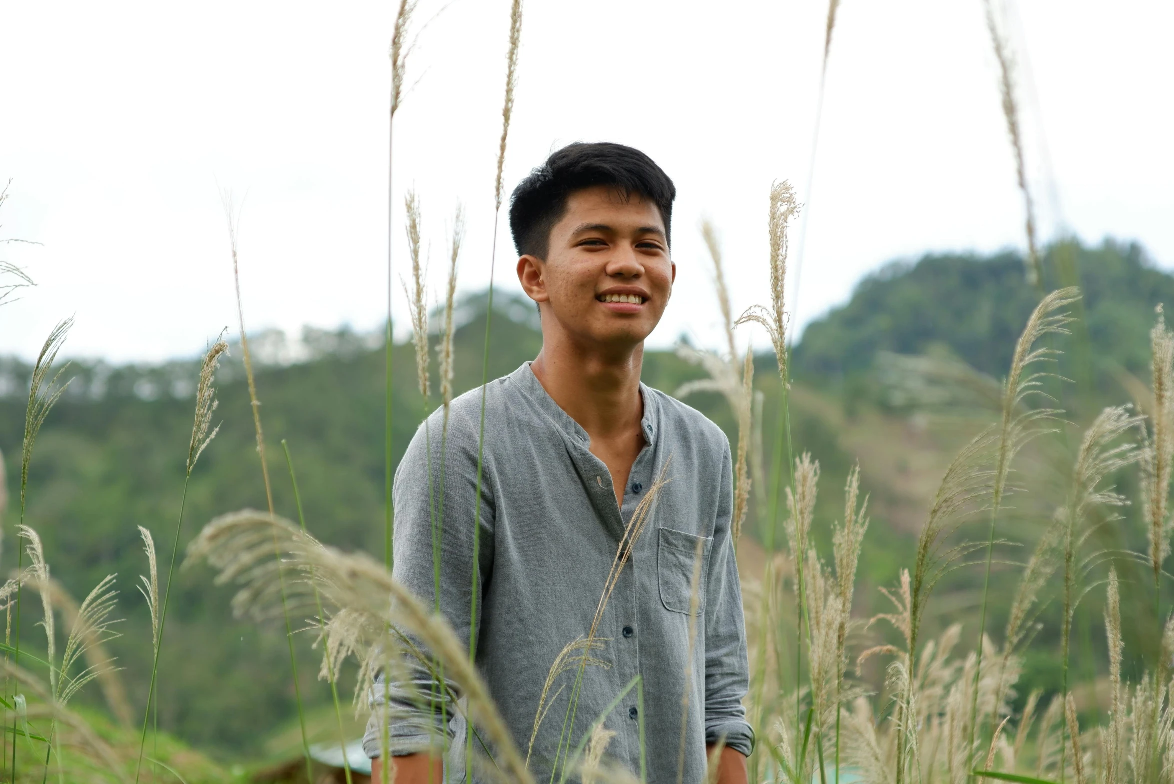 a young man is standing among the tall grass