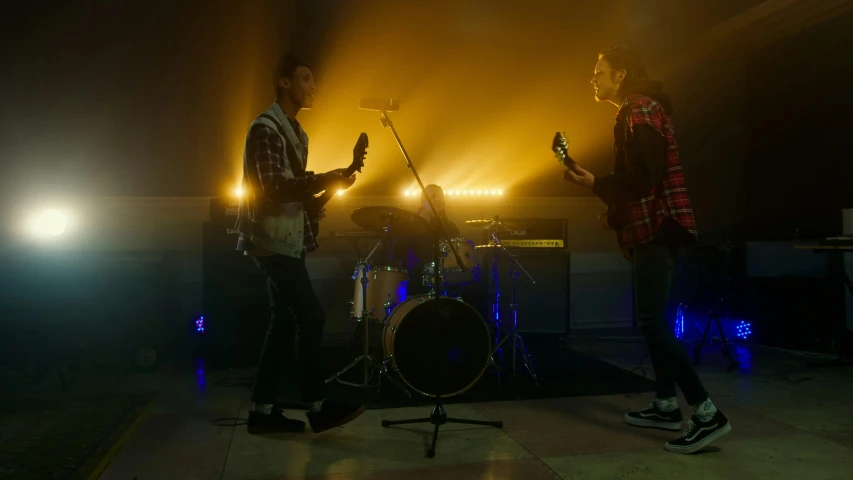 two men are standing on a stage playing instruments