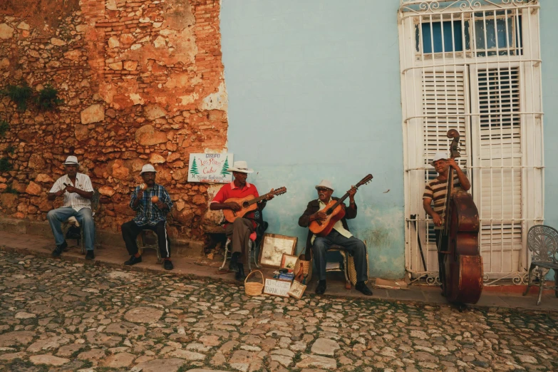 three men sitting on the curb with instruments in front of them