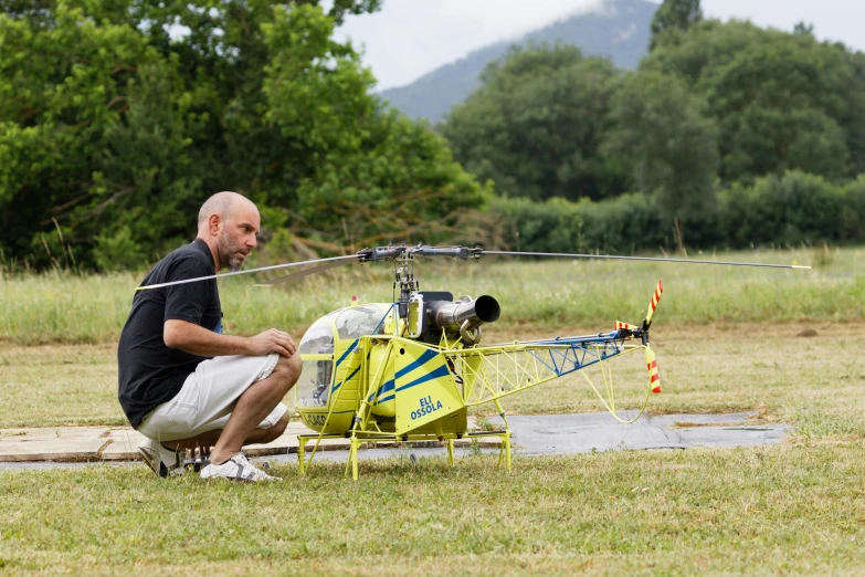 a man kneeling down with a helicopter on a runway