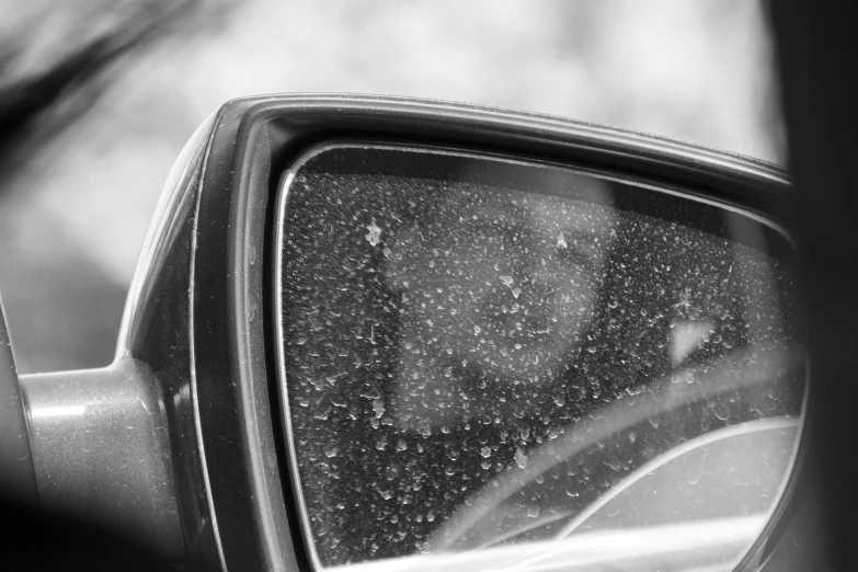 the rear view mirror of a car with tiny snow flakes on it