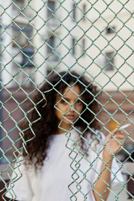 woman in white shirt behind a wire fence