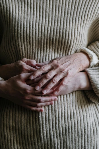 a woman in a sweater holding her hands together