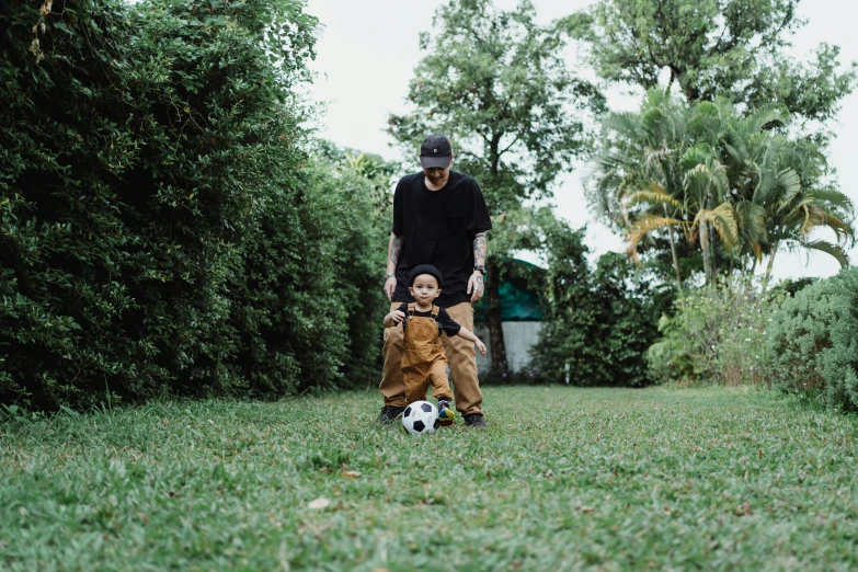 a man and a little boy are playing with soccer balls