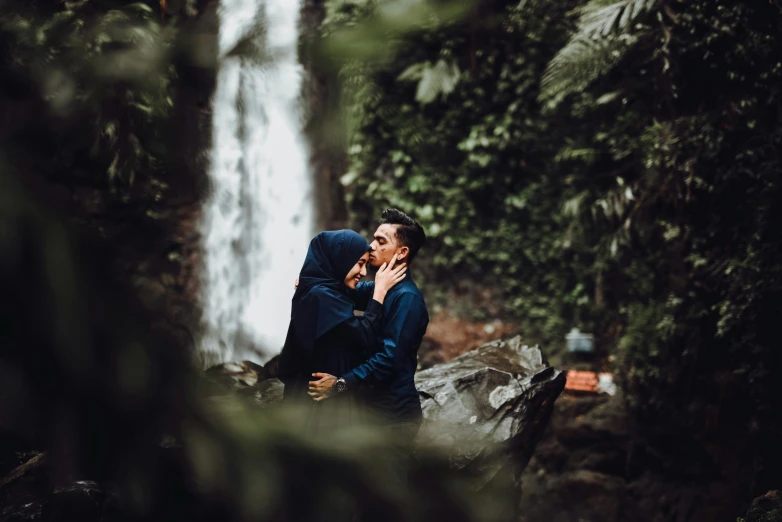 the two people are in front of a waterfall