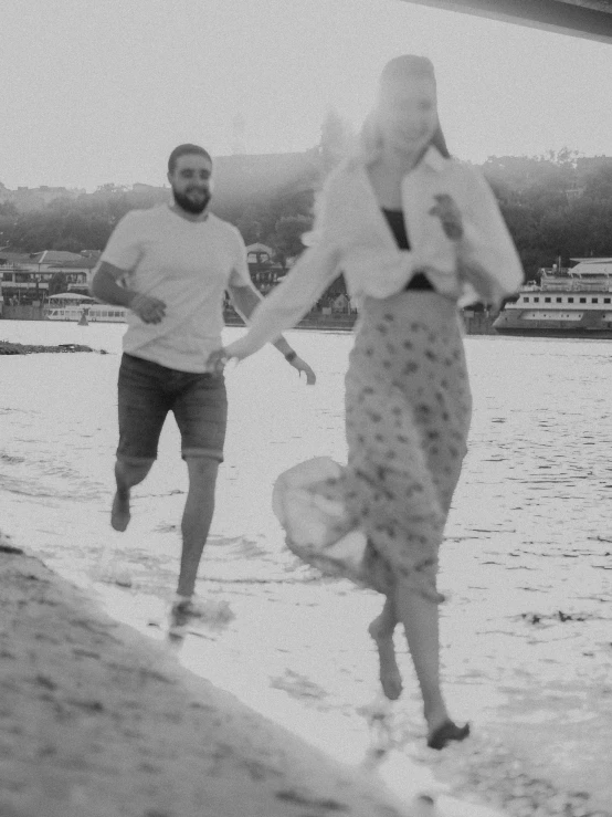 two people walk on a beach near the water